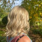 Woman with dry blonde hair outdoors.